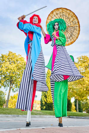 Creative stilt walkers with umbrella and sword performing show in parkの写真素材
