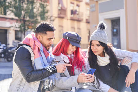 Diverse friends using smartphone on city streetの写真素材