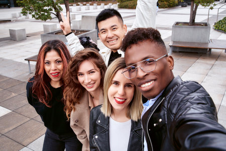 From above African American man smiling and taking a selfie with multiracial friends on a weekend day on the street.の写真素材