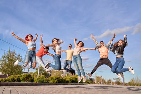Group of happy friends smiling at camera while jumping together outdoors. Friendship and happiness concept.の写真素材