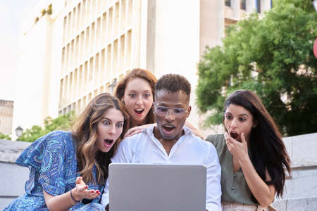Group of multiracial people looking shocked while looking something at the laptop screen. Urban lifestyle and technology concept.の写真素材