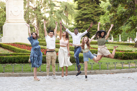 Group of multi-ethnic friends smiling and jumping while having fun together outdoors in a park. Friendship concept.の写真素材