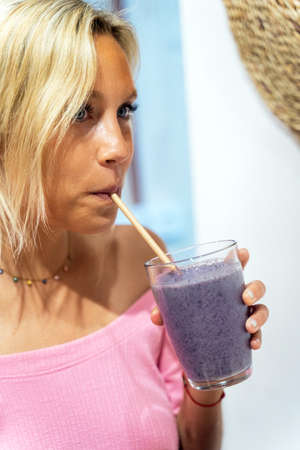 Close-up view of a woman drinking a fresh smoothie in a cafe. Healthy lifestyle and drinks concept.の写真素材