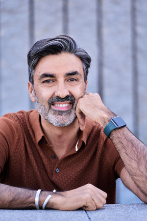 Portrait of a middle-aged man looking at camera and smiling outdoors.
