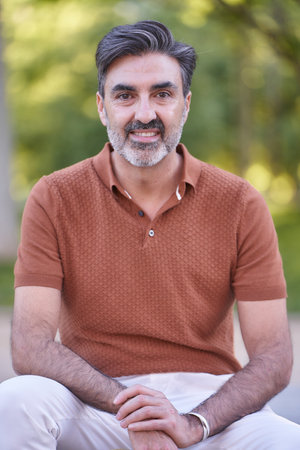 Close-up view of a relaxed middle-aged man looking at camera while standing outdoors in a park.の写真素材