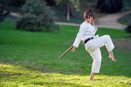 Karate fighter woman in white kimono and black belt practicing karate outdoors. Sports and martial arts concept.の写真素材