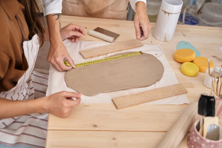 Woman measuring clay with a meter in a pottery workshop. Woman learning to work the clay Crafts...