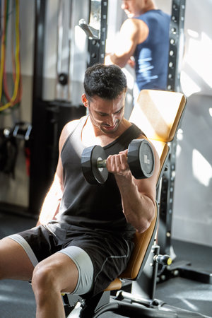 Fit young Caucasian man working out with weights at the gym