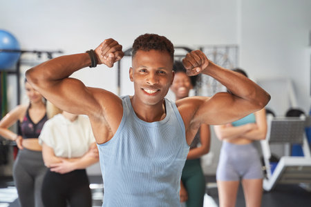 Black man posing on camera with his group of fitness friends at the gymの写真素材