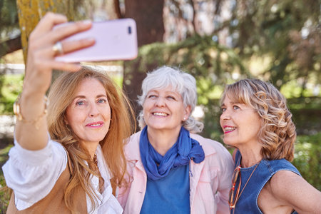 Three senior women share a fun moment taking a selfie with their phone, proving that age is just a...