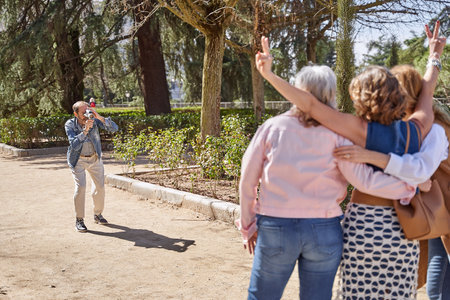 A man with a vintage video camera captures memories with his three friends, preserving their special moments with an old-school touchの写真素材