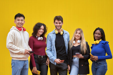 Multi-ethnic friends with headphones looking at camera while holding mobile phones. Technology and friendship concept.の写真素材