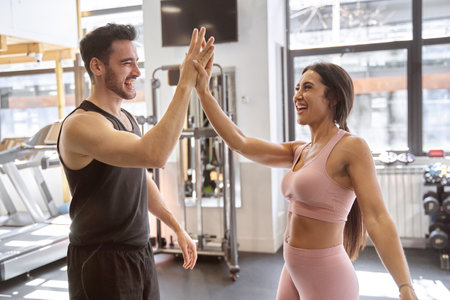 brunette fitness couple high-fiving very happy after finishing their workout at the gymの写真素材