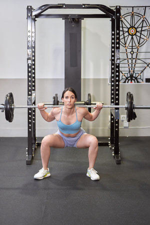 Young athlete tense ready to perform shoulder press exercise with heavy barbell. Healthy living conceptの写真素材