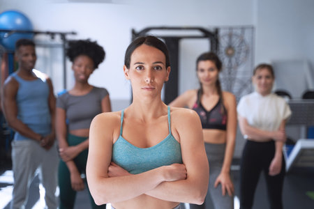 Confident woman posing with arms crossed in front of the group in the gym. Sport concept.の写真素材