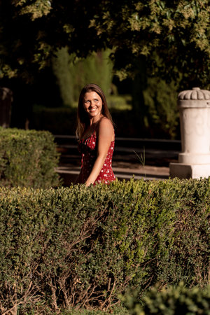 Joyful woman lit by sunlight smiling while enjoying walking outdoors in a park.の写真素材