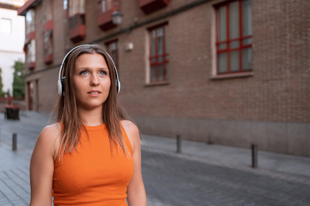 Woman listening to music with headphones while walking on the street. Technology concept.