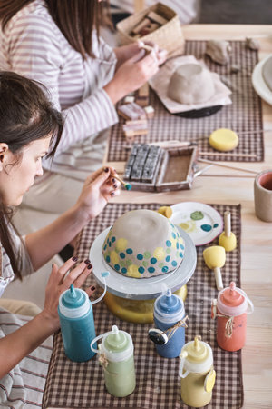 Woman painting a ceramic bowl in a pottery class. Hobby and craft concept.の写真素材