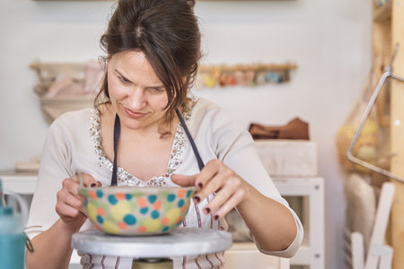 Potter woman finishing a craft in her ceramic workshop. Hobby and craft concept.の写真素材