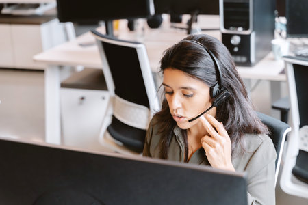 Woman using a headset while working in the office. Business and technology concept.の写真素材
