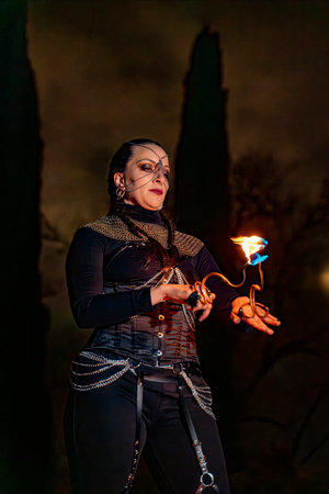 Fire artist performing with a flaming torch during an outdoor night show, creating a captivating...