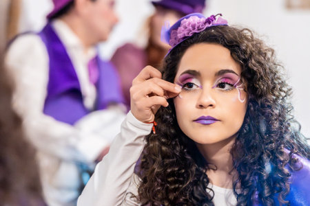 Makeup artist applying fantasy makeup on young actress getting ready for a stage performanceの写真素材