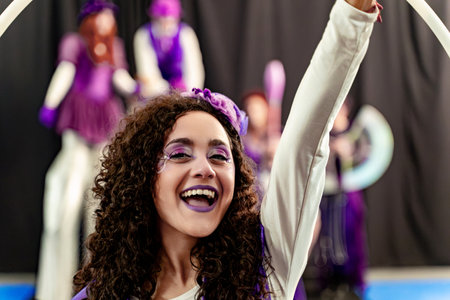 Smiling circus artist with purple makeup performing, her colleagues blurred in the backgroundの写真素材