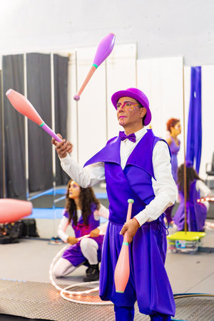 Male artist juggling with clubs during a circus school training with other artists in the backgroundの写真素材