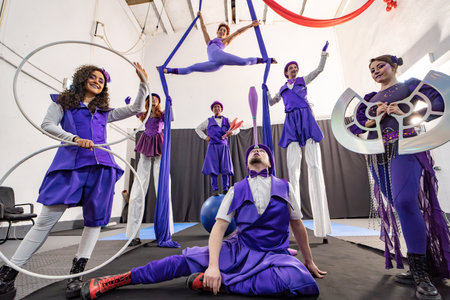 Circus performers in vibrant purple costumes displaying skills like hula hooping, juggling, and aerial acrobaticsの写真素材