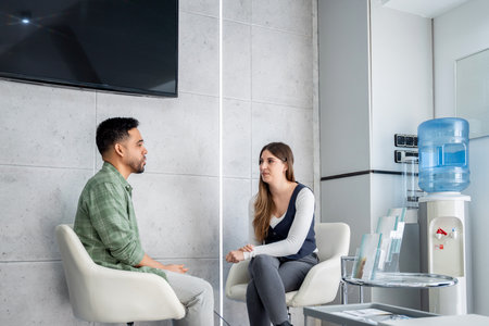Two business people having a conversation in a modern office waiting room, discussing work related mattersの写真素材