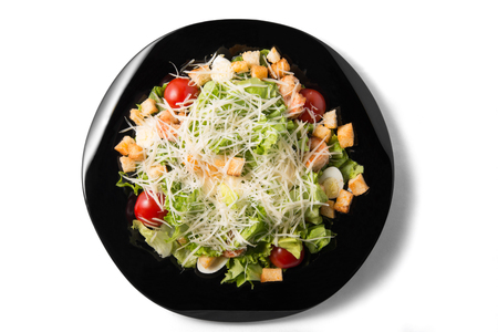 Caesar salad with prawns, cherry tomato and cheese on black plateの写真素材