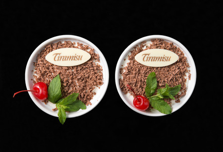 Tiramisu dessert on black background top view, with chocolate, decorated by cherry and mintの写真素材