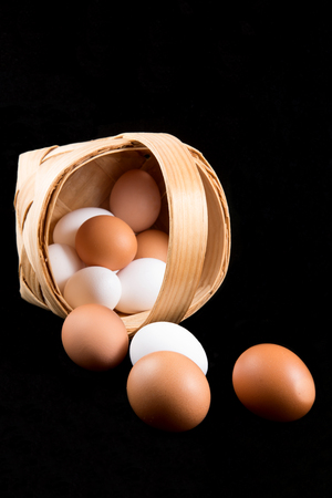 Eggs in a birch bark basket on black backgroundの写真素材
