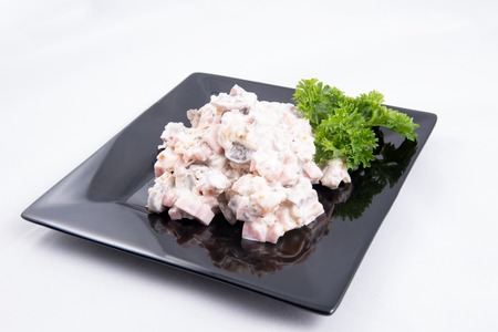 Salad with fish, mushrooms, and mayonnaise on black plateの写真素材