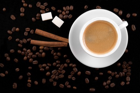 Coffee cup, coffee beans, cinnamon sticks and sugar on black backgroundの写真素材