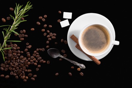 Coffee cup, coffee beans, cinnamon sticks and sugar on black backgroundの写真素材