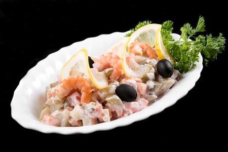 Salad with prawns, fish, potatoes and mayonnaise, decorated by parsley on black backgroundの写真素材