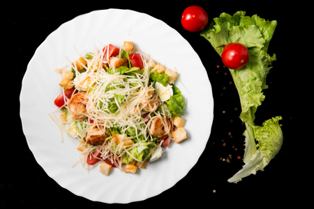 Caesar salad with prawns, cherry tomato and cheese on white plateの写真素材