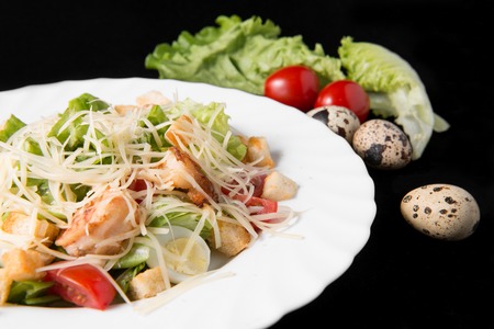 Caesar salad with prawns, cherry tomato and cheese on white plateの写真素材