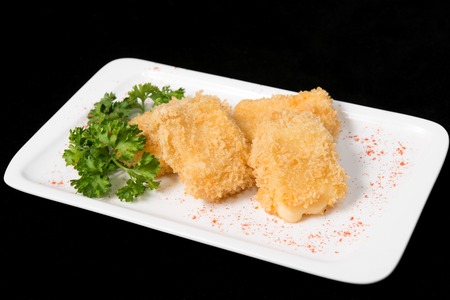 Fried cheese suluguni on white plate on black backgroundの写真素材