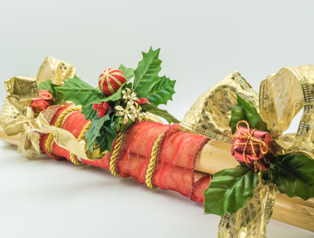 Pieces of cane adorned with red cloth, golden string and leaves with Christmas motifs.の写真素材