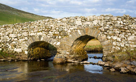 Evening light on an old crooked bridge over a trout stream in Connemara, County Galway, Irelandの写真素材