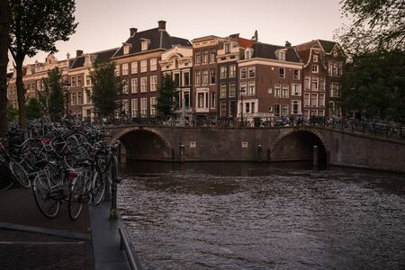 Houses and bikes beside the canal at sunset, Amsterdam, Netherlandsの写真素材