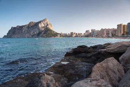 View from the rocks of the coastline with the urban beach of Calpe and the crag in the background, Alicante, Spainの写真素材