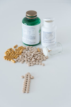 Transparent capsules with yellow powder and light brown pills on white background close up top view...