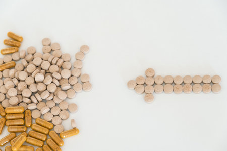Transparent capsules with yellow powder and light brown pills on white background close up top view with copy spaceの写真素材
