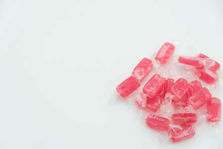 Red candies in transparent wrapper on white background close up top view with copy spaceの写真素材