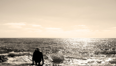 Man sitting at the ocean beachの写真素材