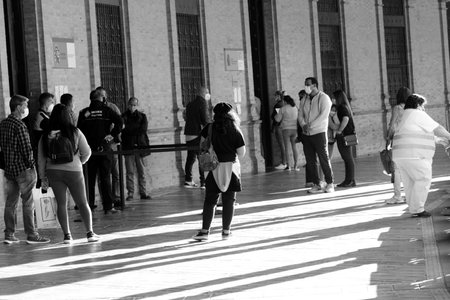 Theseare people waiting in Spain square in Seville, in one of its aisles with columns