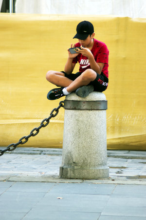 This photo is part of an assignment in a photo walk. A teen is sdiiting on a boundadary stoneのeditorial素材